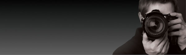 Person holding a camera, dark background.