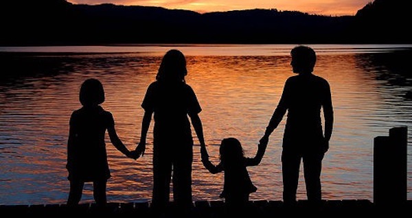 Silhouetted family holding hands at sunset.