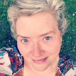 Smiling person lying on grass, colorful shirt.