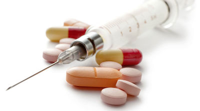 Syringe and pills on white background.