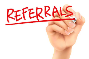 Hand writing the word "referrals" in red.