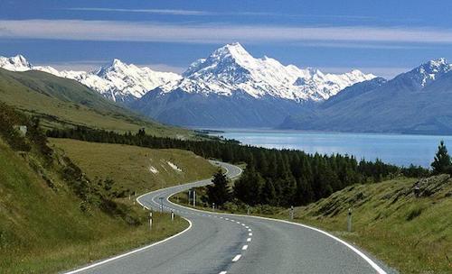 Winding road with snow-capped mountains background.
