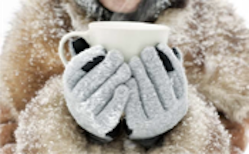 Gloved hands holding mug in snowy coat.
