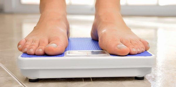 Feet standing on a blue bathroom scale.